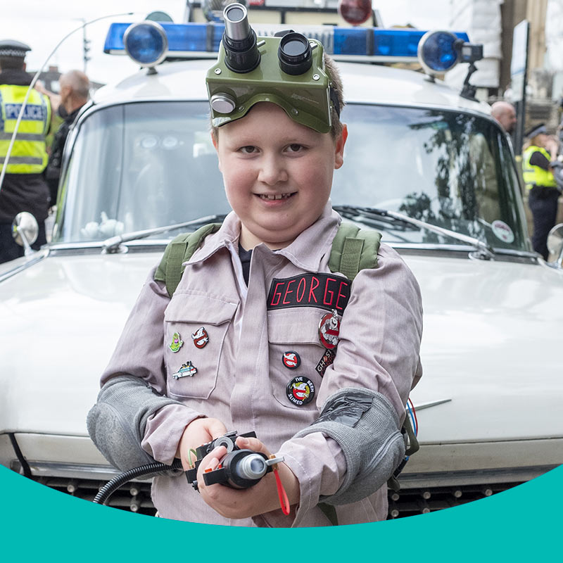 Wish child, George standing in front of Ecto-1 in his Ghostbuster uniform