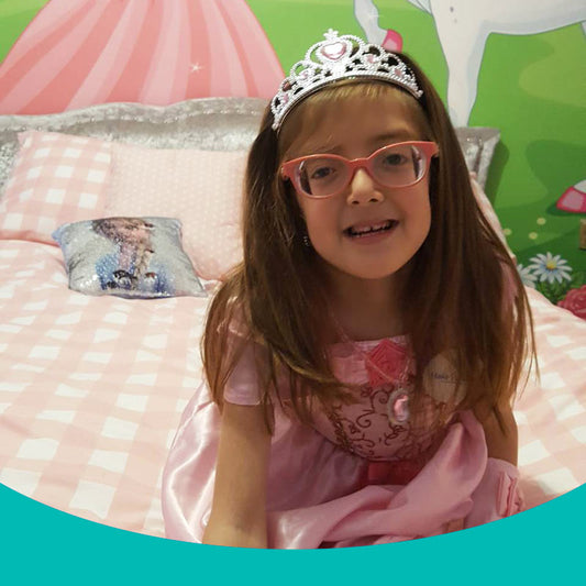 Wish child, Tiara in her princess-themed bedroom, wearing a pink dress and tiara.